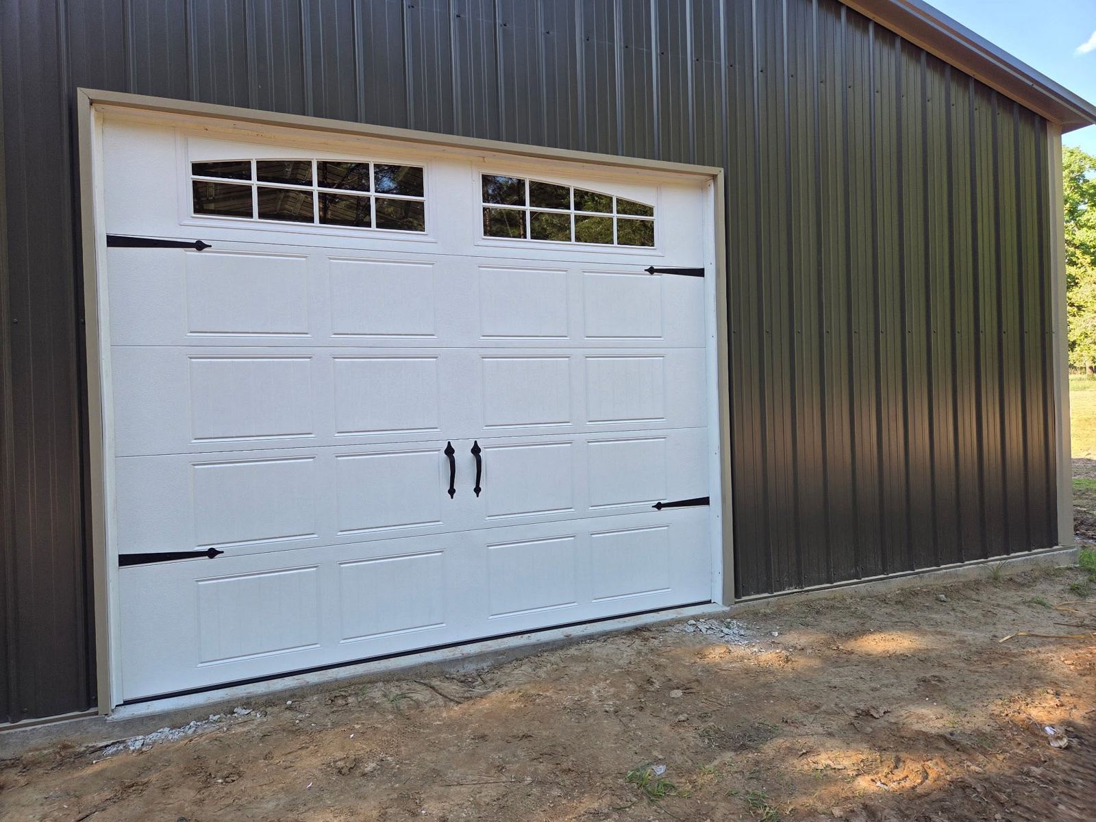 New white carriage garage door on dark metal building